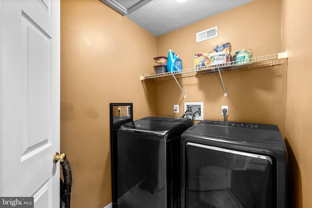 clothes washing area with laundry area, a textured ceiling, visible vents, and separate washer and dryer