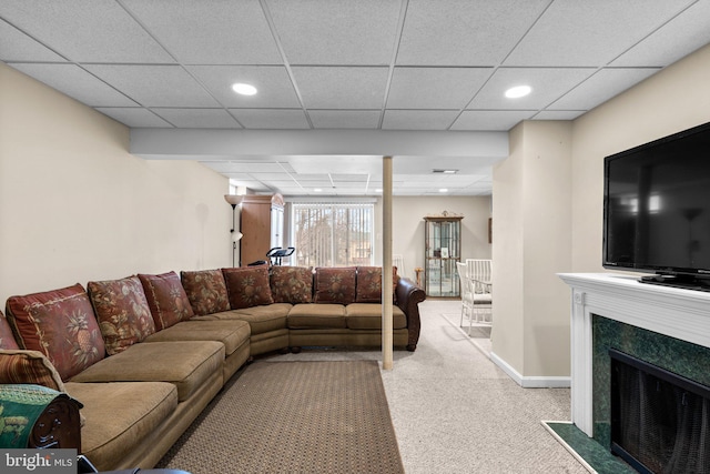 living room featuring a high end fireplace, baseboards, carpet, recessed lighting, and a paneled ceiling