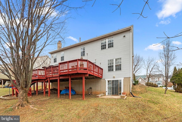 back of property with a yard, a wooden deck, and a chimney