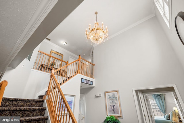 stairs featuring a high ceiling, an inviting chandelier, and ornamental molding