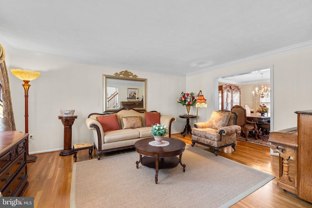 living area with light wood-style flooring, an inviting chandelier, and ornamental molding