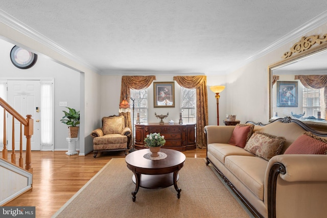 living area with plenty of natural light, a textured ceiling, wood finished floors, and crown molding