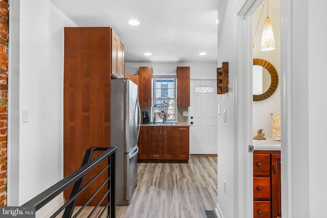 kitchen featuring backsplash, freestanding refrigerator, recessed lighting, light wood-style floors, and light countertops