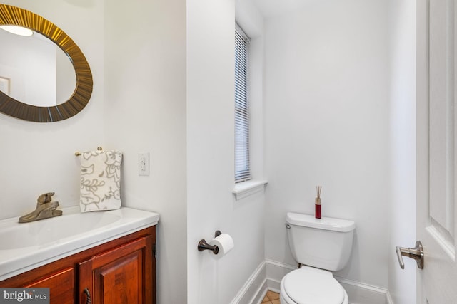 bathroom with toilet, vanity, and baseboards