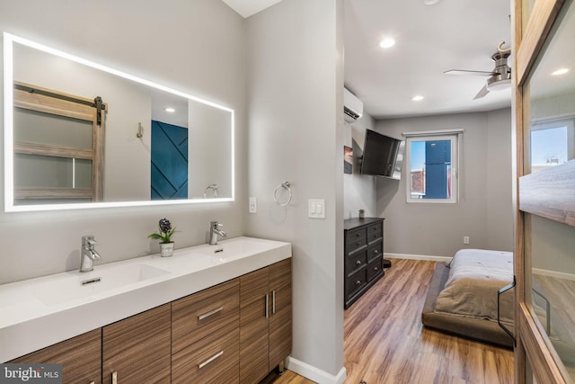 bathroom with a wall mounted air conditioner, wood finished floors, a ceiling fan, and a sink