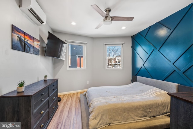 bedroom featuring a wall mounted air conditioner, baseboards, light wood-style floors, and recessed lighting