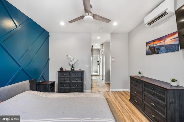 bedroom with recessed lighting, light wood-type flooring, a wall mounted air conditioner, and baseboards