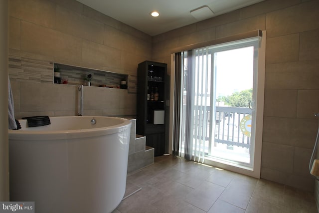 full bathroom with a tub, tile walls, recessed lighting, and tile patterned flooring