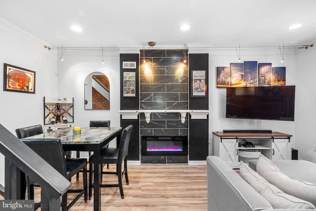 dining area with crown molding, recessed lighting, wood finished floors, and a premium fireplace