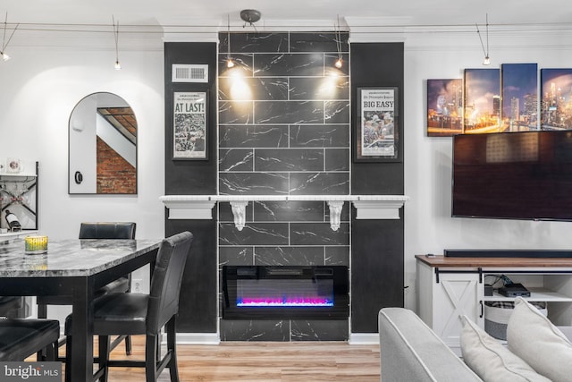 dining space featuring visible vents, ornamental molding, a fireplace, and wood finished floors