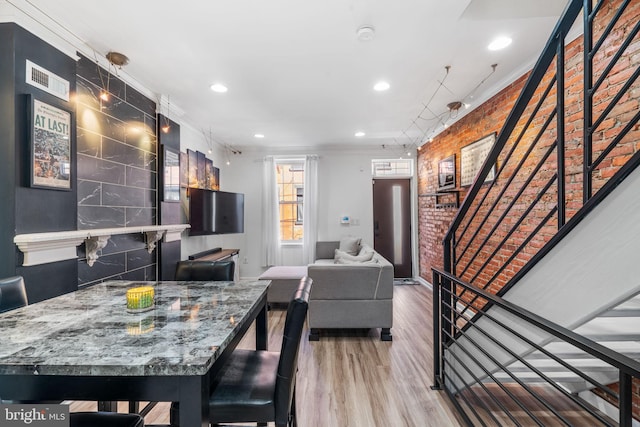 dining room with stairway, wood finished floors, brick wall, recessed lighting, and crown molding