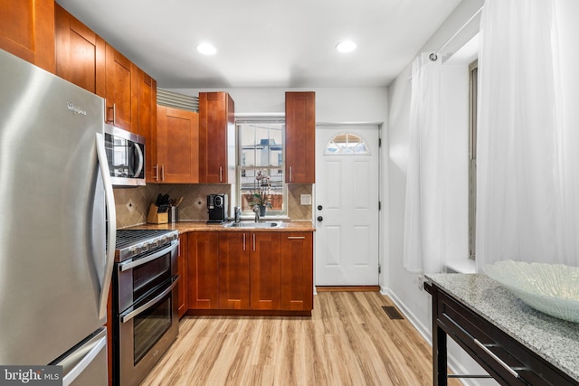 kitchen featuring visible vents, a sink, tasteful backsplash, stainless steel appliances, and light wood-style floors