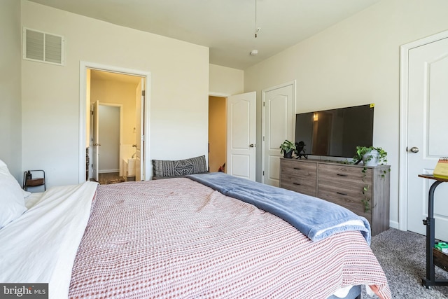 carpeted bedroom featuring visible vents and ensuite bath