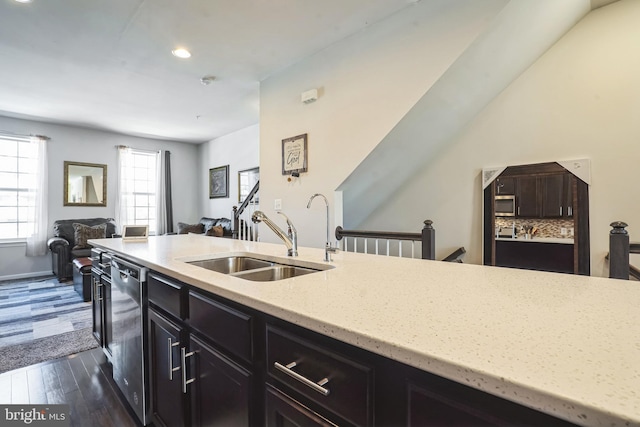 kitchen featuring open floor plan, dark wood-type flooring, a sink, light stone counters, and dishwasher