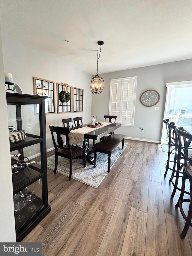 dining area with baseboards, a notable chandelier, and wood finished floors