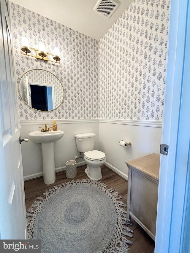 bathroom with visible vents, toilet, a sink, wood finished floors, and baseboards