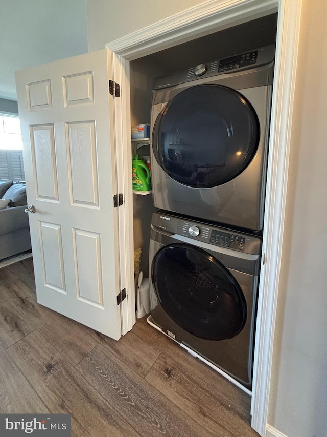 laundry area with dark wood-style flooring, laundry area, and stacked washing maching and dryer