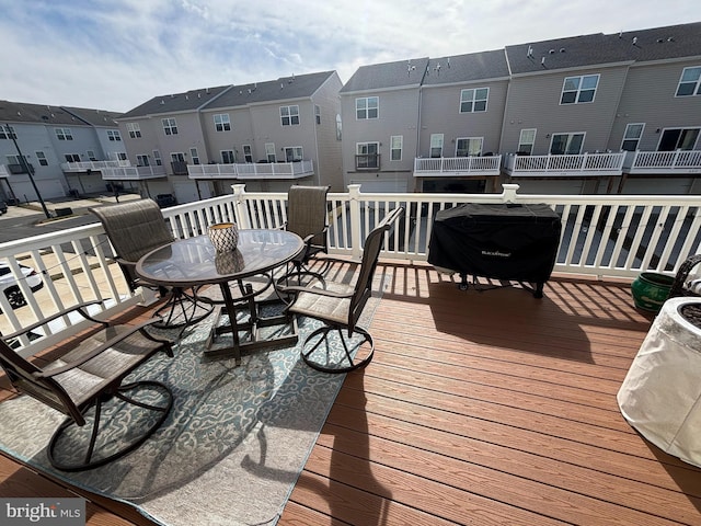 wooden terrace with a residential view, a grill, and outdoor dining space