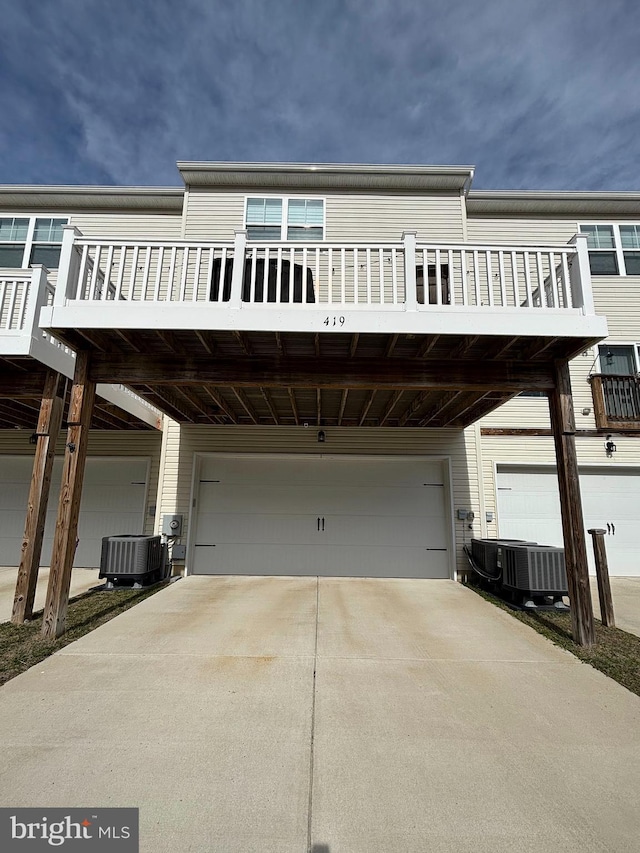 view of front of house featuring concrete driveway, an attached garage, and central AC unit