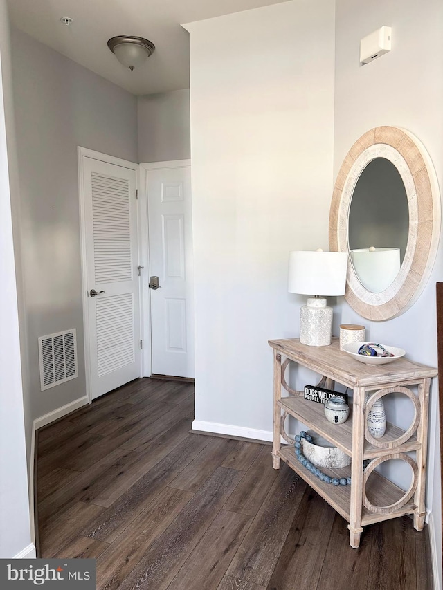 hall with dark wood finished floors, baseboards, and visible vents