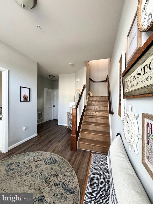 stairway with visible vents, baseboards, and wood finished floors