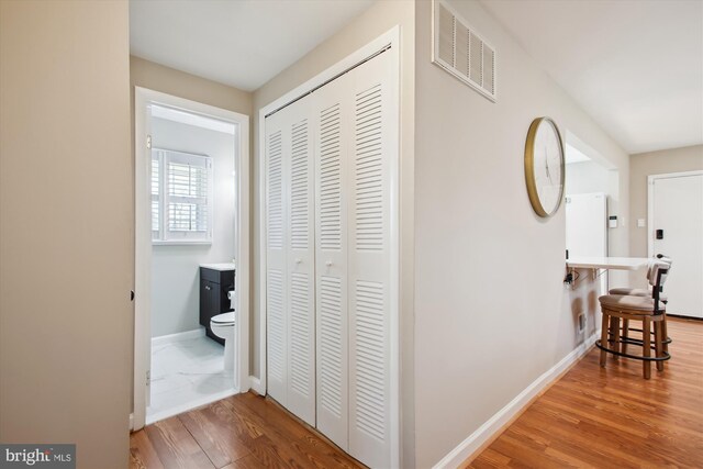 corridor featuring visible vents, baseboards, and wood finished floors