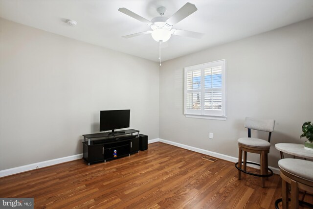 sitting room featuring visible vents, baseboards, wood finished floors, and a ceiling fan