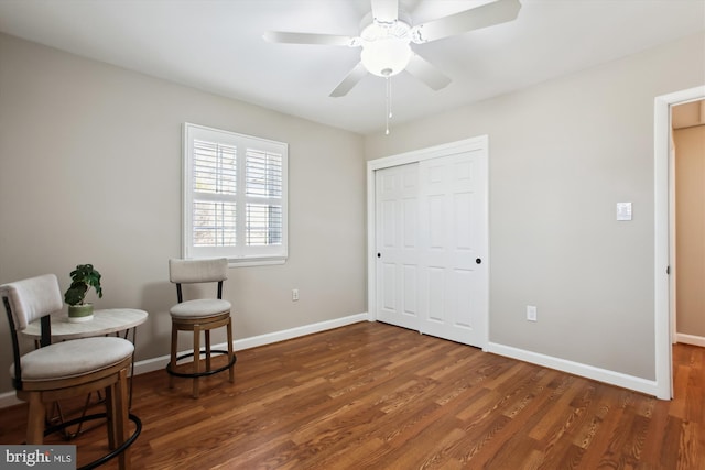 sitting room with a ceiling fan, baseboards, and wood finished floors