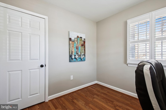 unfurnished office featuring baseboards and dark wood-type flooring