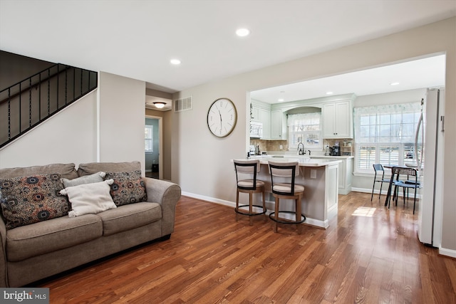 living room featuring visible vents, recessed lighting, baseboards, and wood finished floors