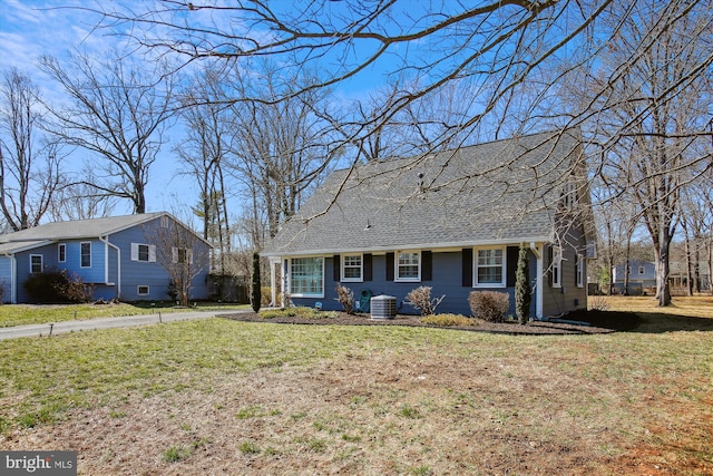 view of front of house with roof with shingles, central AC, and a front lawn