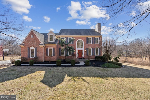 view of front facade featuring a front yard, brick siding, and a chimney