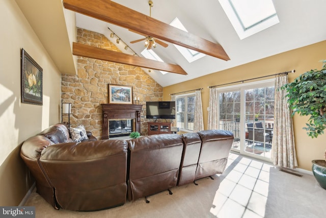 tiled living area with high vaulted ceiling, a skylight, a fireplace, ceiling fan, and beamed ceiling