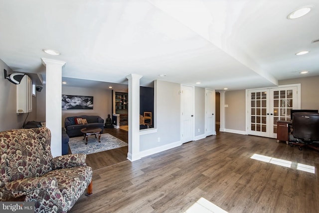 living room featuring french doors, baseboards, wood finished floors, and ornate columns