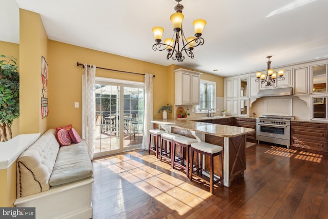 kitchen featuring a peninsula, a sink, dark wood-type flooring, high end stainless steel range, and a chandelier