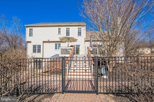 rear view of house with a fenced front yard and a gate