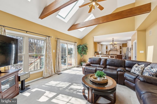 living area featuring a skylight, ceiling fan with notable chandelier, light colored carpet, and high vaulted ceiling