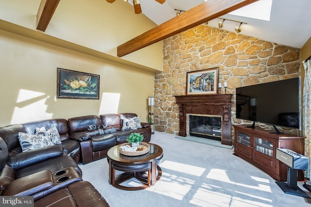 carpeted living area with vaulted ceiling with beams, ceiling fan, and a fireplace