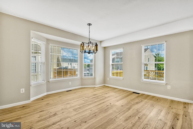 unfurnished dining area with light wood-style flooring, a notable chandelier, visible vents, and baseboards