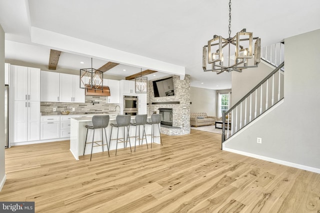 kitchen with white cabinetry, open floor plan, light wood finished floors, and a chandelier