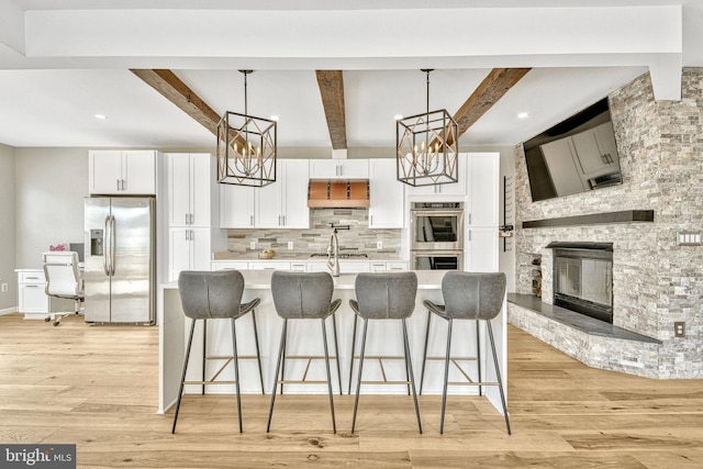 kitchen featuring stainless steel appliances, backsplash, light wood-style flooring, and light countertops