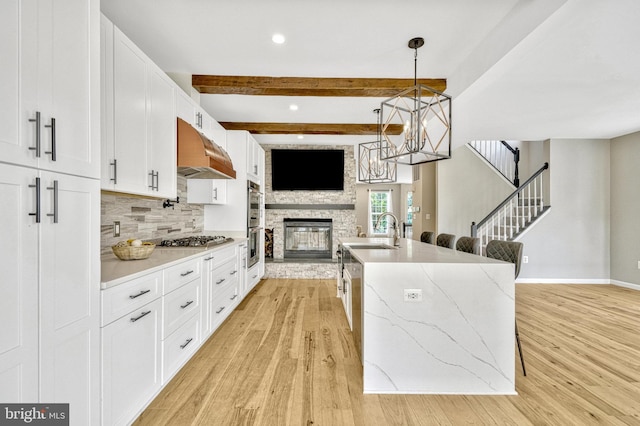 kitchen with an inviting chandelier, a fireplace, a sink, under cabinet range hood, and open floor plan