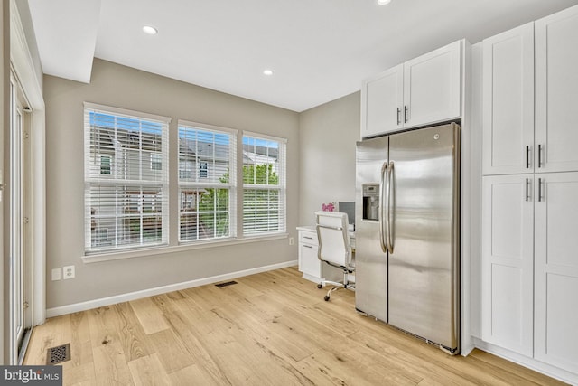 kitchen featuring light wood finished floors, visible vents, baseboards, stainless steel fridge with ice dispenser, and white cabinets