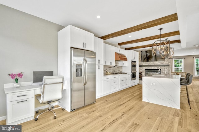 kitchen with under cabinet range hood, light wood-type flooring, appliances with stainless steel finishes, and a sink