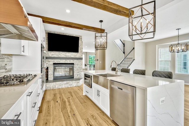 kitchen featuring premium range hood, an inviting chandelier, light wood-style flooring, stainless steel appliances, and open floor plan