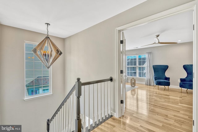 hall featuring an inviting chandelier, wood finished floors, an upstairs landing, and baseboards