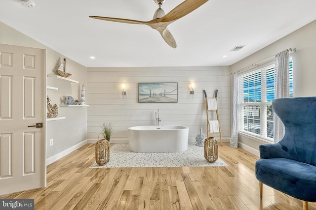 full bathroom with a freestanding tub, wood finished floors, visible vents, and baseboards