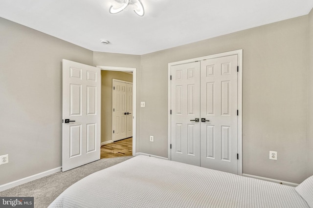 carpeted bedroom featuring baseboards and a closet