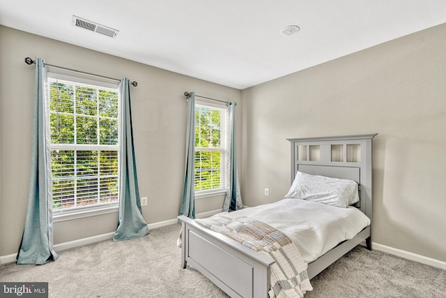 bedroom with visible vents, light carpet, and baseboards