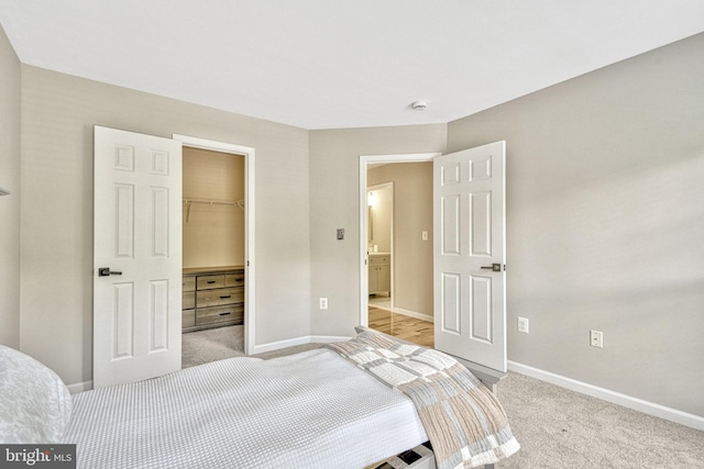 bedroom featuring a walk in closet, baseboards, and carpet floors